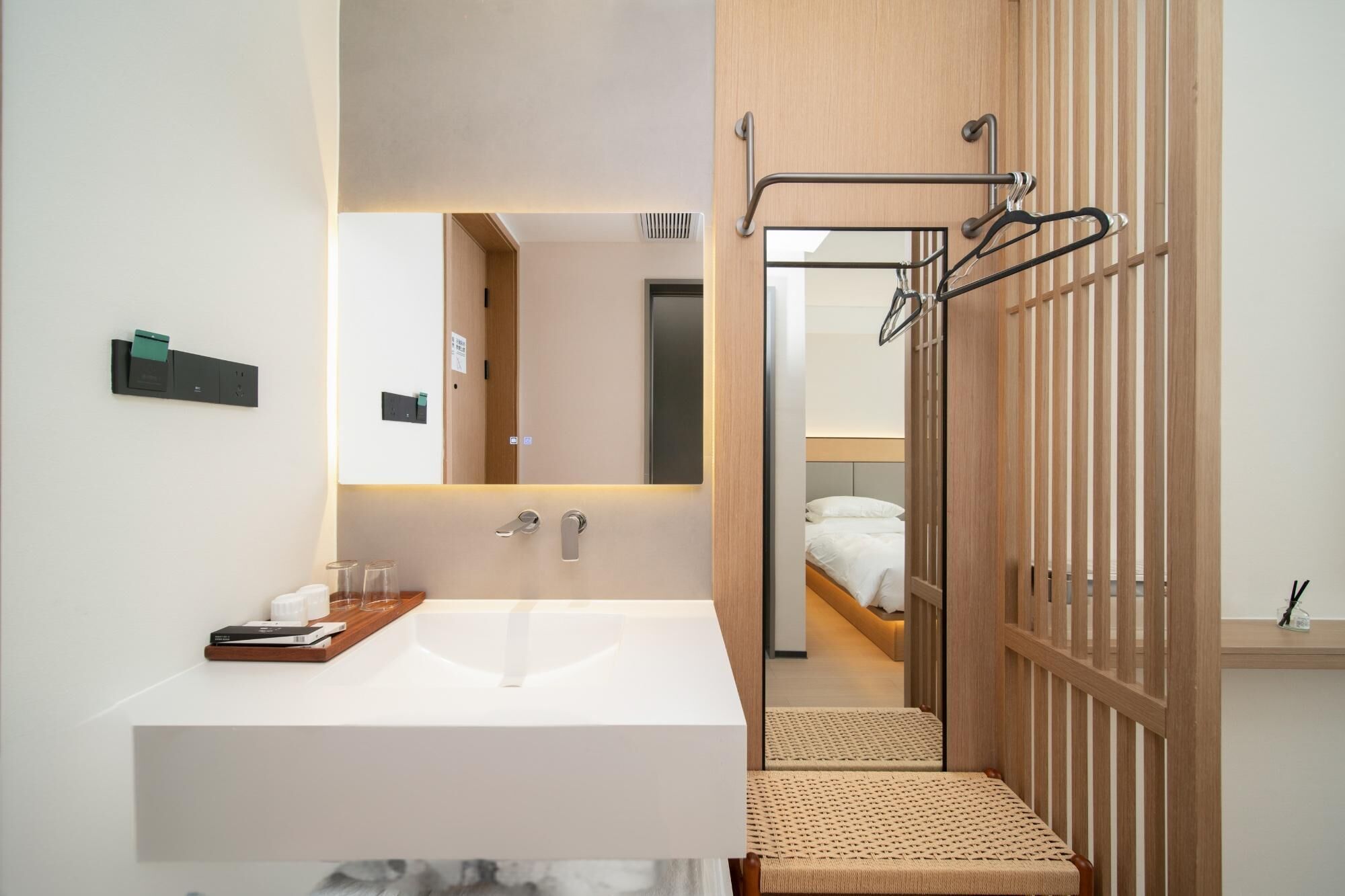 A modern bathroom with a large sink, a mirror, and a shower area with a wooden partition.