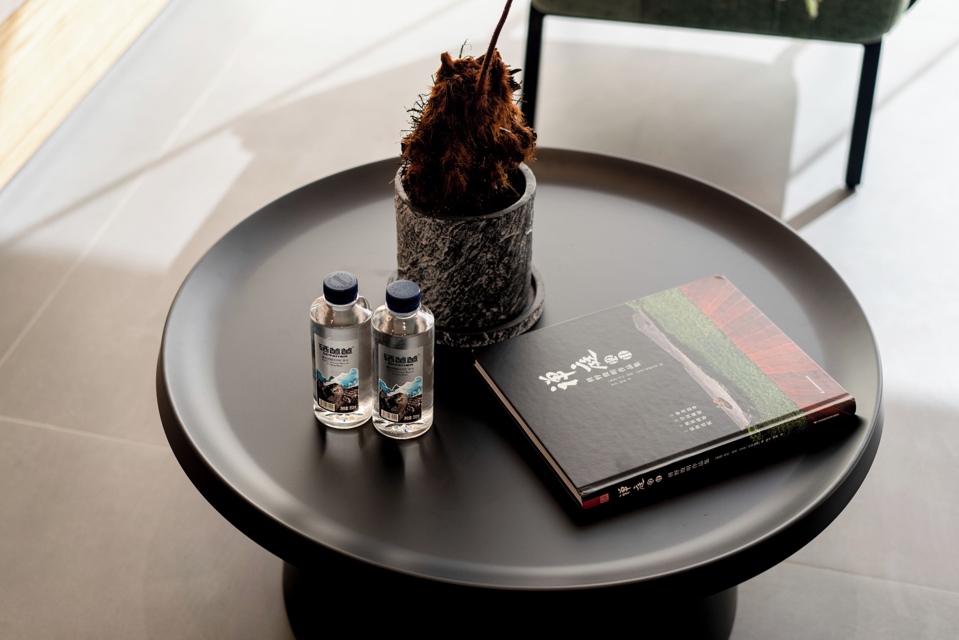 A round table with a book, two bottles, and a decorative item.