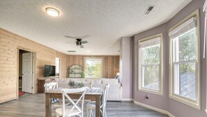Une pièce spacieuse avec un plancher en bois, une table à manger avec des chaises, un canapé et de grandes fenêtres.
