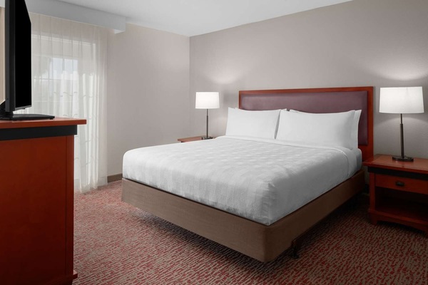 Drift off in a spacious bed beside airy window light.