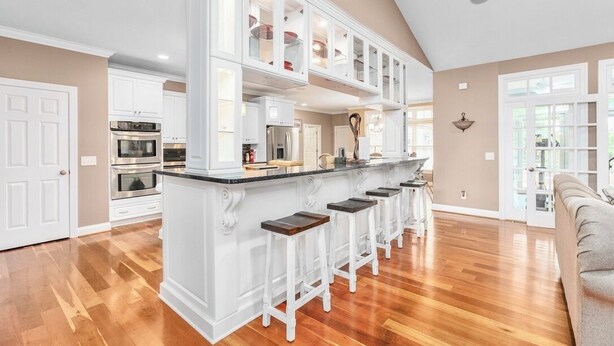 A spacious kitchen with white cabinetry, a central island with stools, and a large window providing natural light. - Spacious & Private Retreat Near Downtown & NC Zoo! (Asheboro)