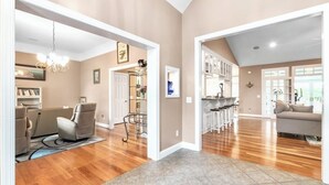 A spacious living area with hardwood flooring, a dining area with a chandelier, and a kitchen with white cabinets. - Spacious & Private Retreat Near Downtown & NC Zoo! (Asheboro)