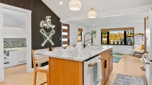 Une cuisine moderne dotée d’un îlot central, de meubles en bois et de luminaires suspendus.