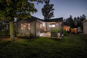 A modern house with a large porch, large windows, and outdoor lighting.