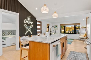 A modern kitchen with a central island, wooden cabinetry, and pendant lighting.