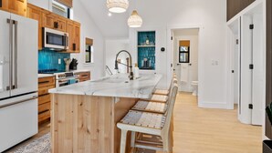 Une cuisine moderne avec des meubles en bois, un îlot central et des luminaires suspendus.