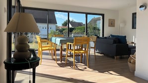 Una sala de estar moderna con comedor, ventanas grandes y vistas al exterior.