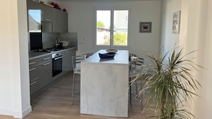 Una cocina moderna con una isla central, electrodomésticos de acero inoxidable y un amplio ventanal que proporciona luz natural.