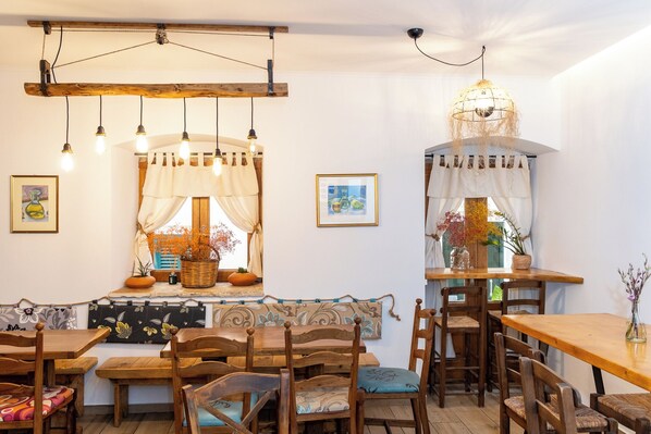 A cozy dining area with wooden furniture, pendant lighting, and decorative elements like framed pictures and potted plants.