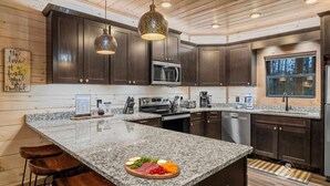 Een moderne keuken met donker houten kasten, granieten aanrecht en roestvrijstalen apparatuur.
