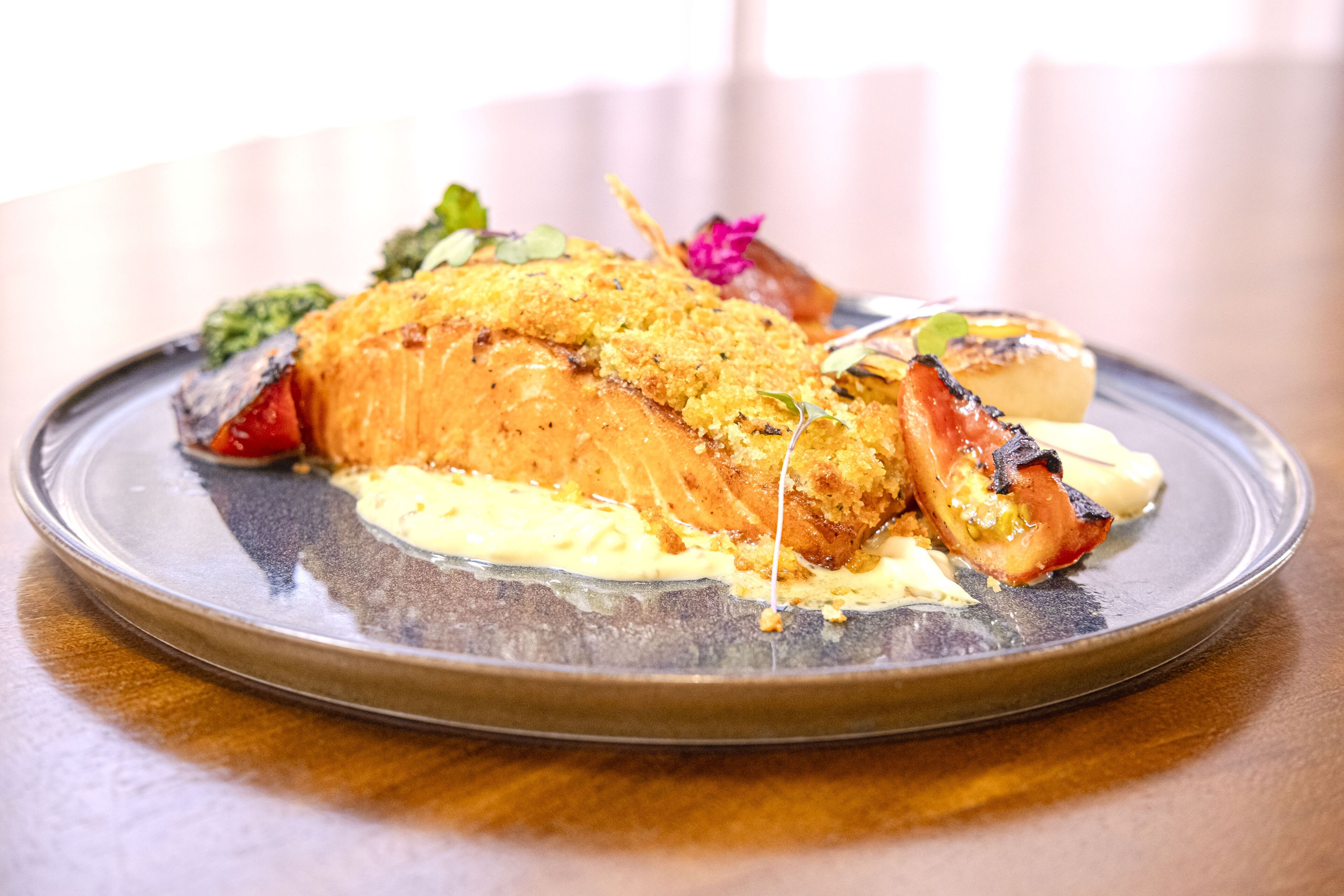 Un plato de comida con salmón, verduras y salsa cremosa.