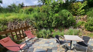 Un patio al aire libre con suelo de piedra, cerca de madera y diversas plantas.