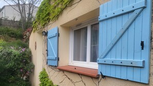 Una casa con contraventanas azules, una ventana y una terraza de madera.