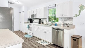A modern kitchen with white cabinets, stainless steel appliances, and a view of greenery outside. - Private Crystal River Getaway Minutes to Springs! (Crystal River)