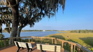 A wooden deck with benches overlooking a body of water and a grassy area. - Private Crystal River Getaway Minutes to Springs! (Crystal River)