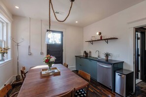 A modern kitchen with a wooden dining table, a built-in sink, and a hanging light fixture. - IVY House | Kansas City (Kansas City)