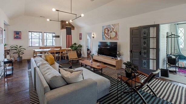 A spacious living room with a large sofa, a dining area, and a television.