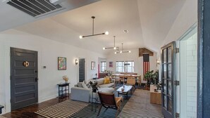 A spacious living area with a sofa, coffee table, and dining table. There is a large window with a view of the outdoors.