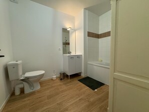 Bathroom features a toilet, sink, and shower area with a tiled wall.