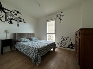 Cozy retreat with a patterned bedspread, wooden floor, and a unique wall decoration.