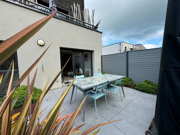 Relax on the patio with a light table and matching chairs, surrounded by lush greenery.