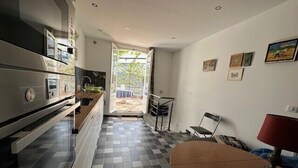 A modern kitchen with a checkered floor, a dining area with a table and chairs, and a view of the outdoors through a glass door. - Charming T2 near beach of Trouville-sur-Mer (Trouville-sur-Mer)