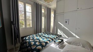 A bedroom with a bed, curtains, and a wardrobe. - Charming T2 near beach of Trouville-sur-Mer (Trouville-sur-Mer)