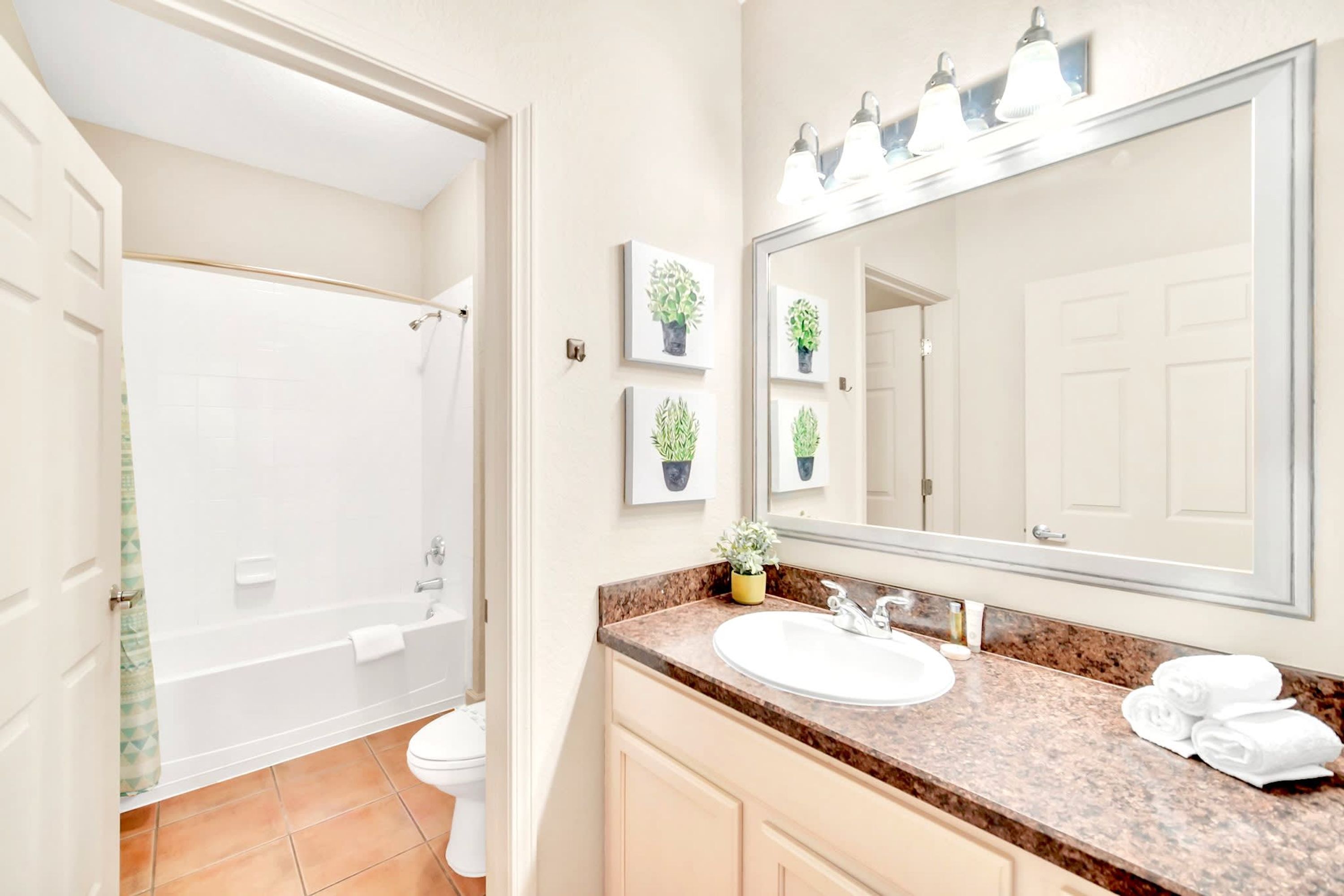 Une salle de bain avec une baignoire, des toilettes, un lavabo et un grand miroir.