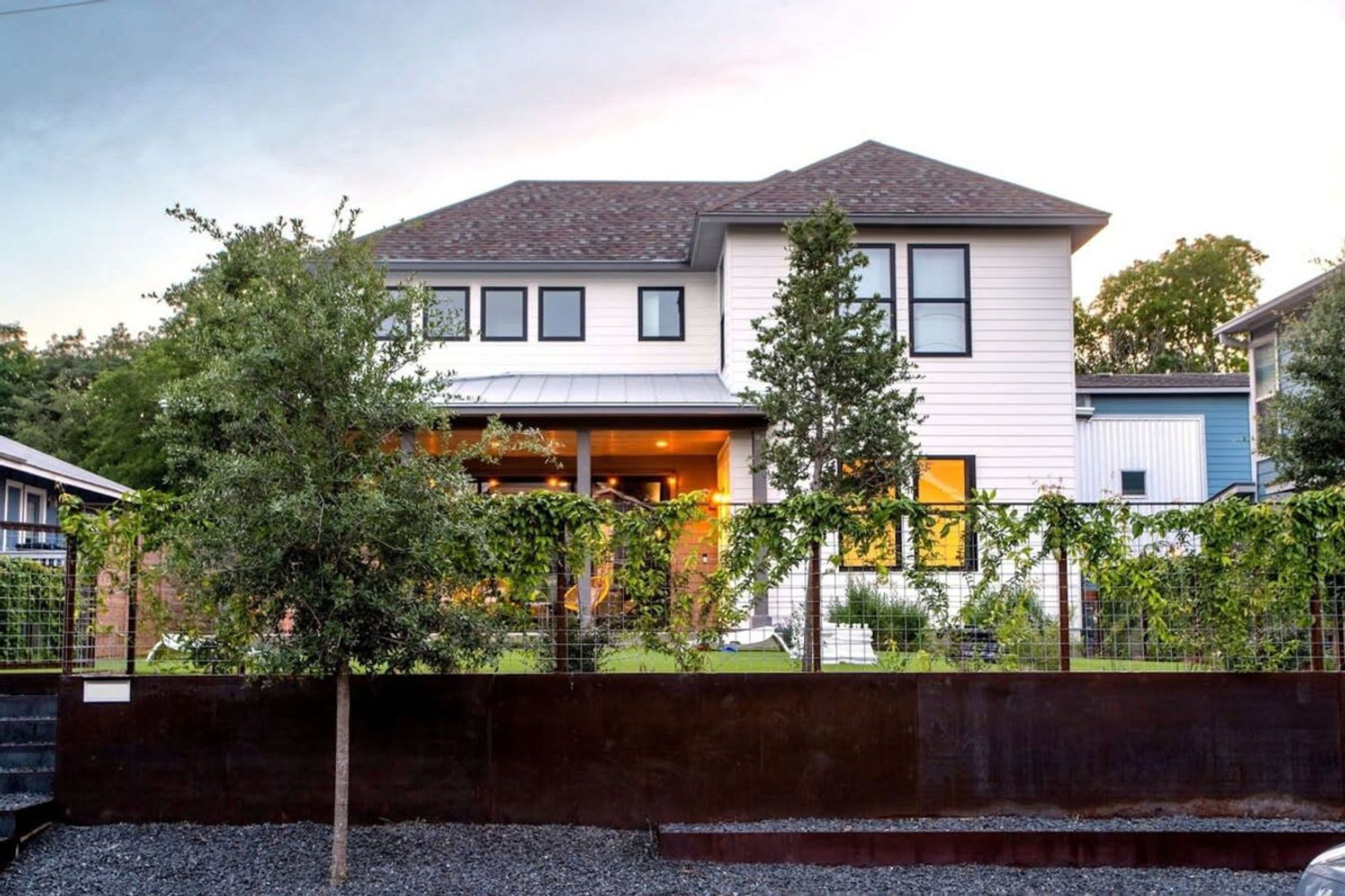 A two-story house with a covered porch and a fenced yard.