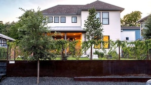 A two-story house with a covered porch and a fenced yard. - Queen s Gambit - 7 min Uber to Downtown ATX (Austin)
