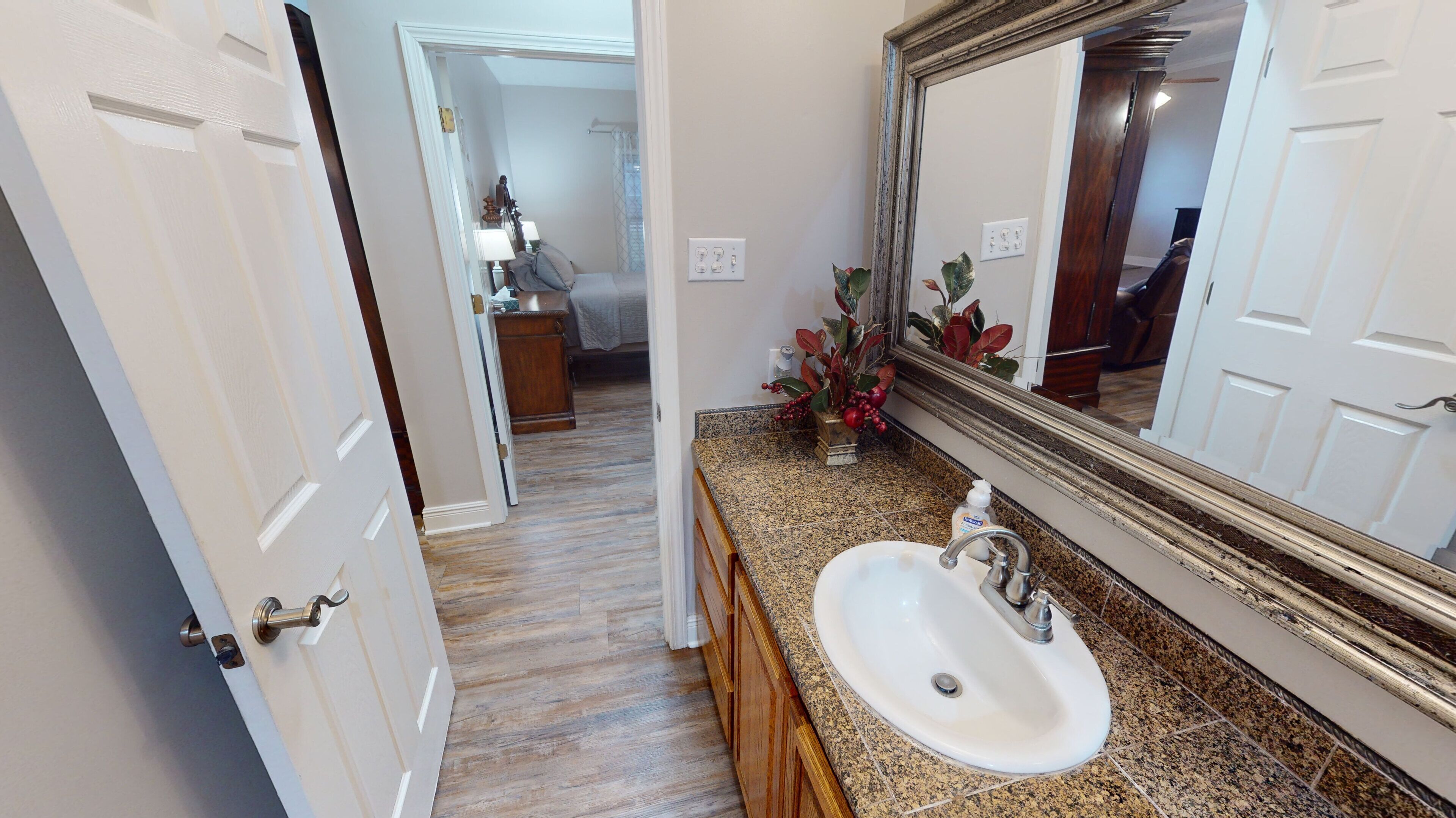 A bathroom with a white sink, granite countertop, and a large mirror.