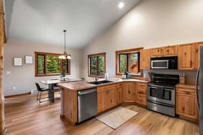 Una cocina moderna con armarios de madera, electrodomésticos de acero inoxidable y ventanas amplias.