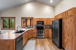 A kitchen with wooden cabinets, a stainless steel refrigerator, a microwave, and a dishwasher.