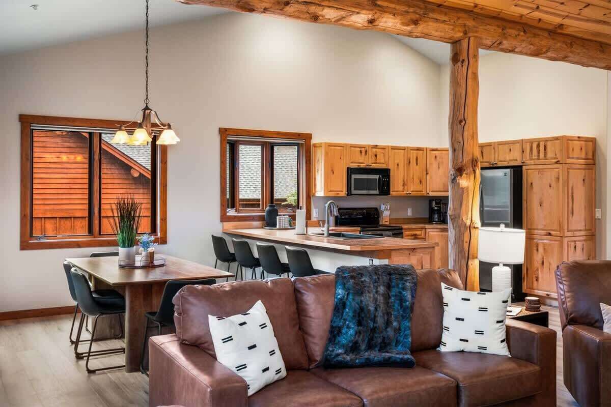 Eine moderne Küche mit Holzschränken, einer zentralen Kücheninsel und einem Essbereich mit einer Ledersofa.