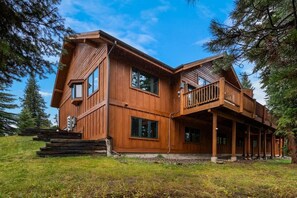 Eine große Holzhütte mit vielen Fenstern und einem Balkon, umgeben von Bäumen.