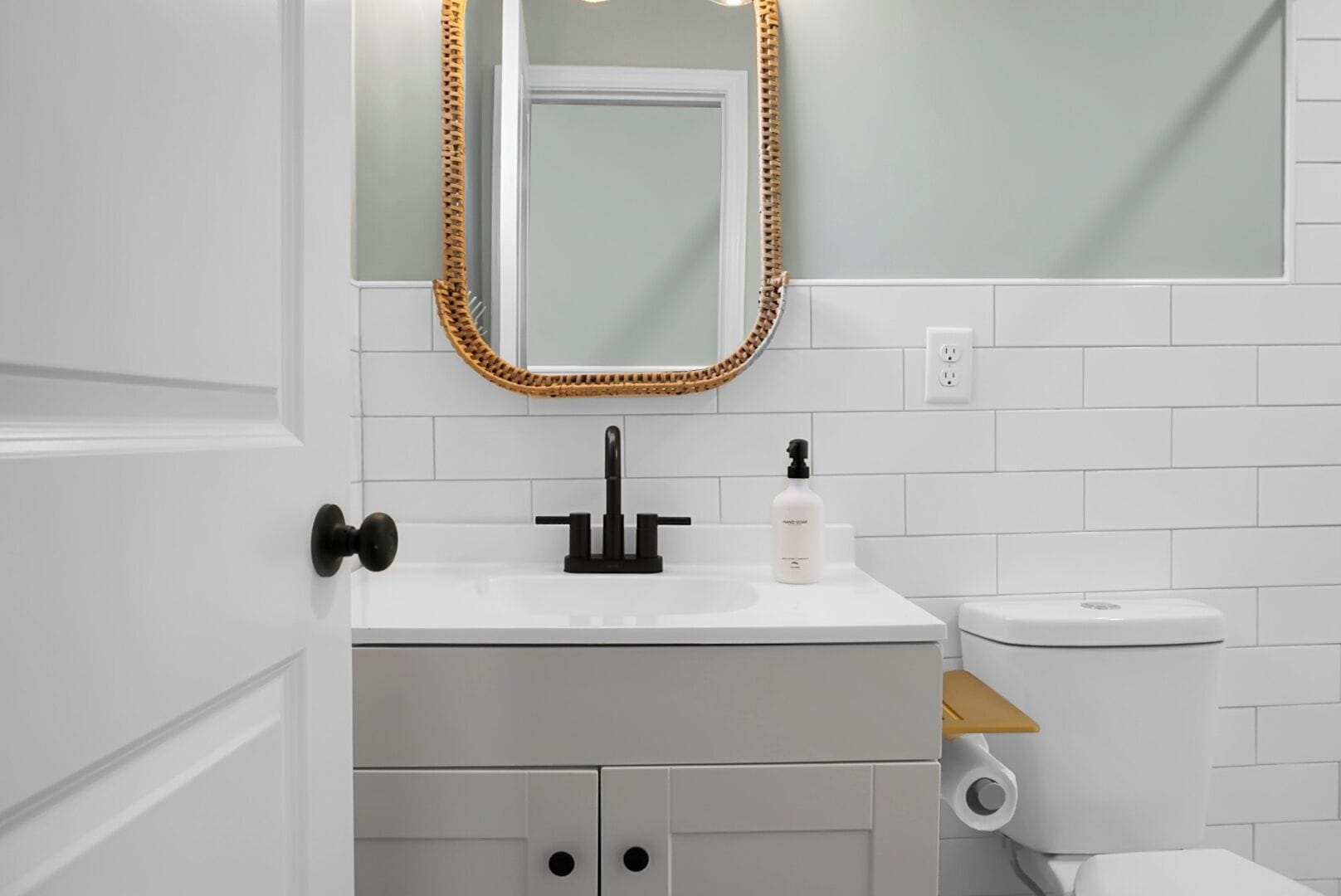 A bathroom with a white sink, black faucet, and a toilet.