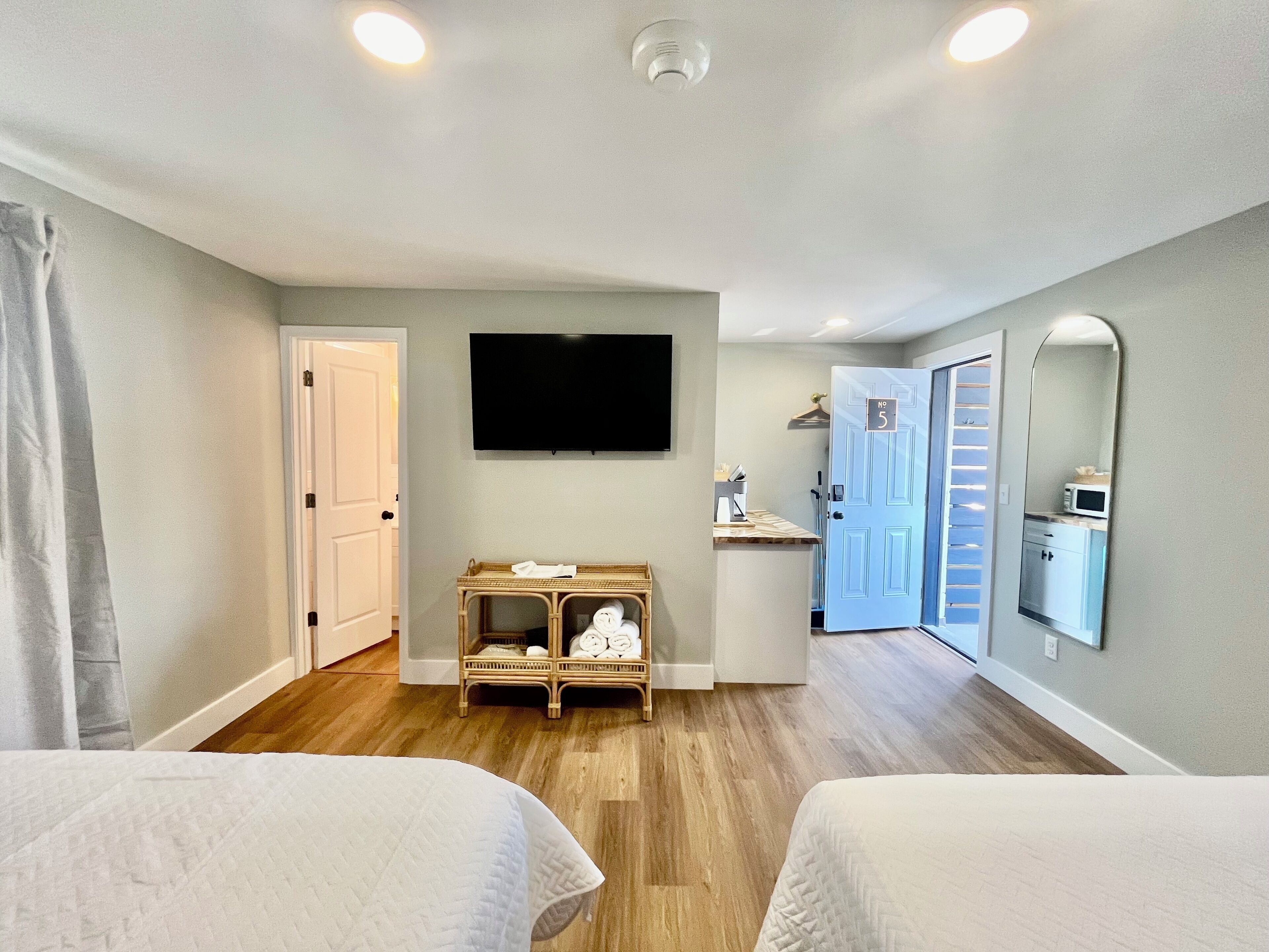 Quarto de hotel com duas camas, uma televisão, uma mesinha com artigos de higiene e um espelho.
