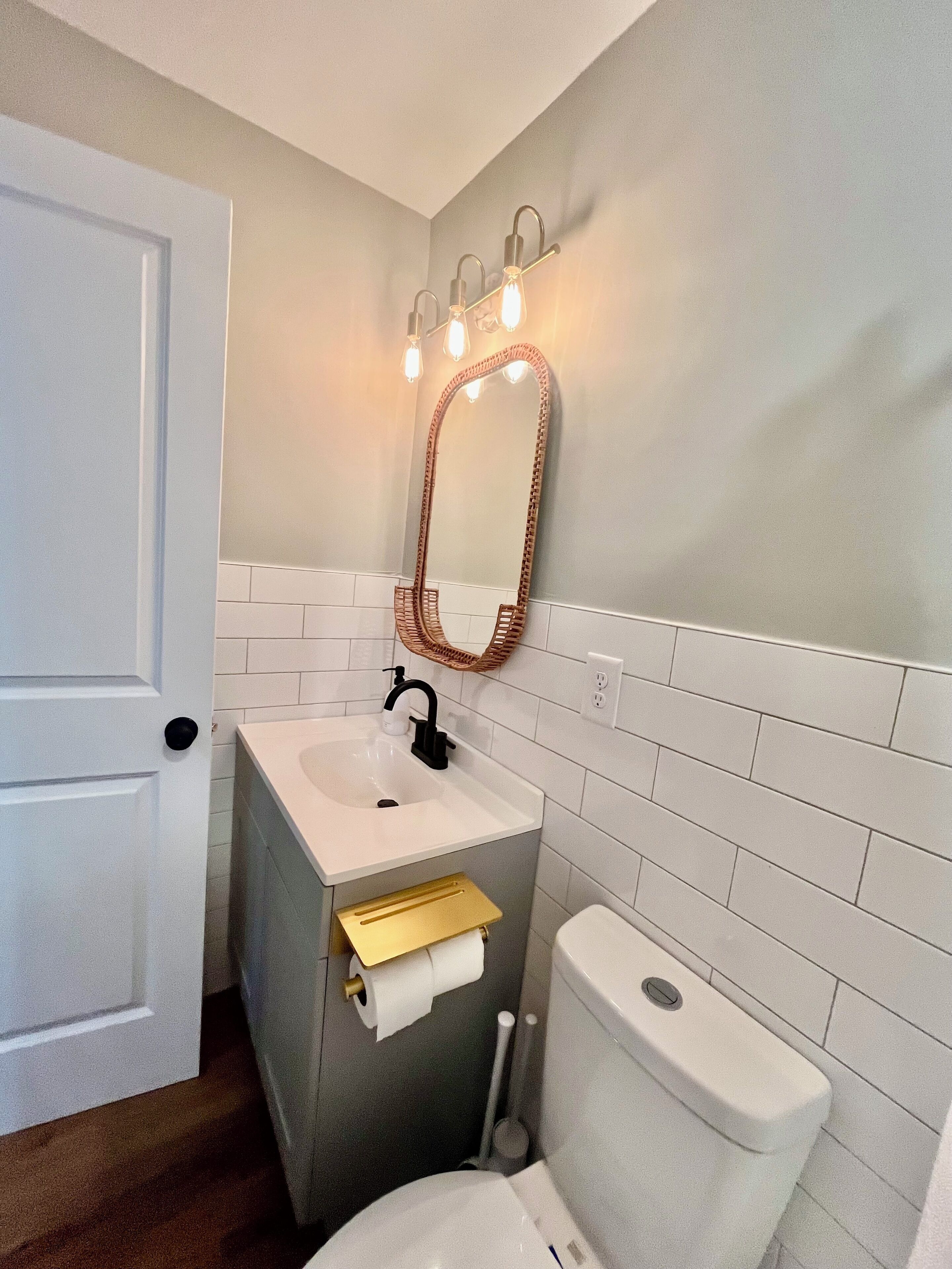 Et badeværelse med en hvid vask, et spejl og et toilet.