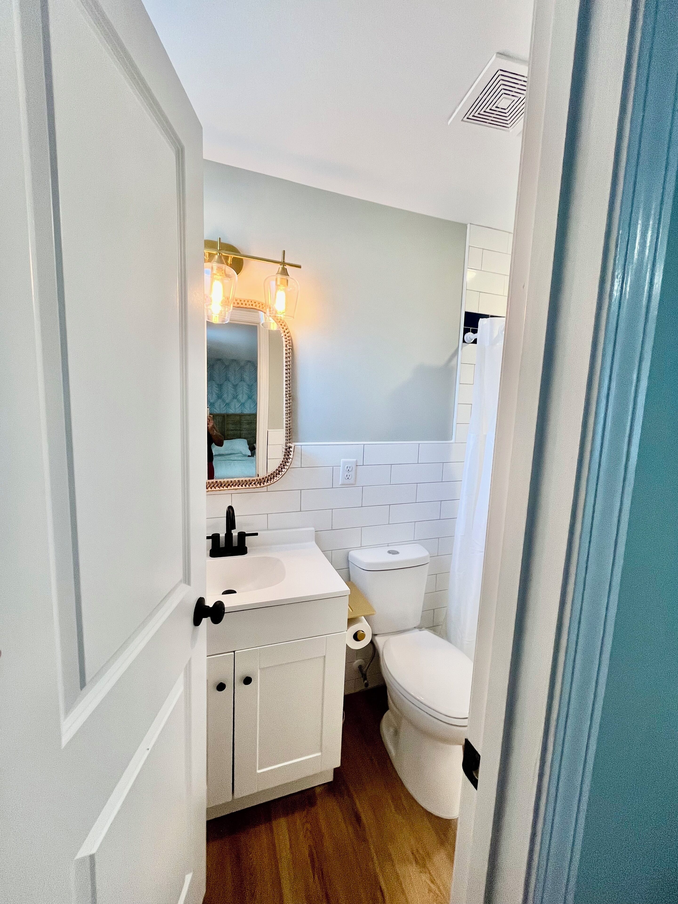A compact bathroom with a white sink, mirror, and toilet.