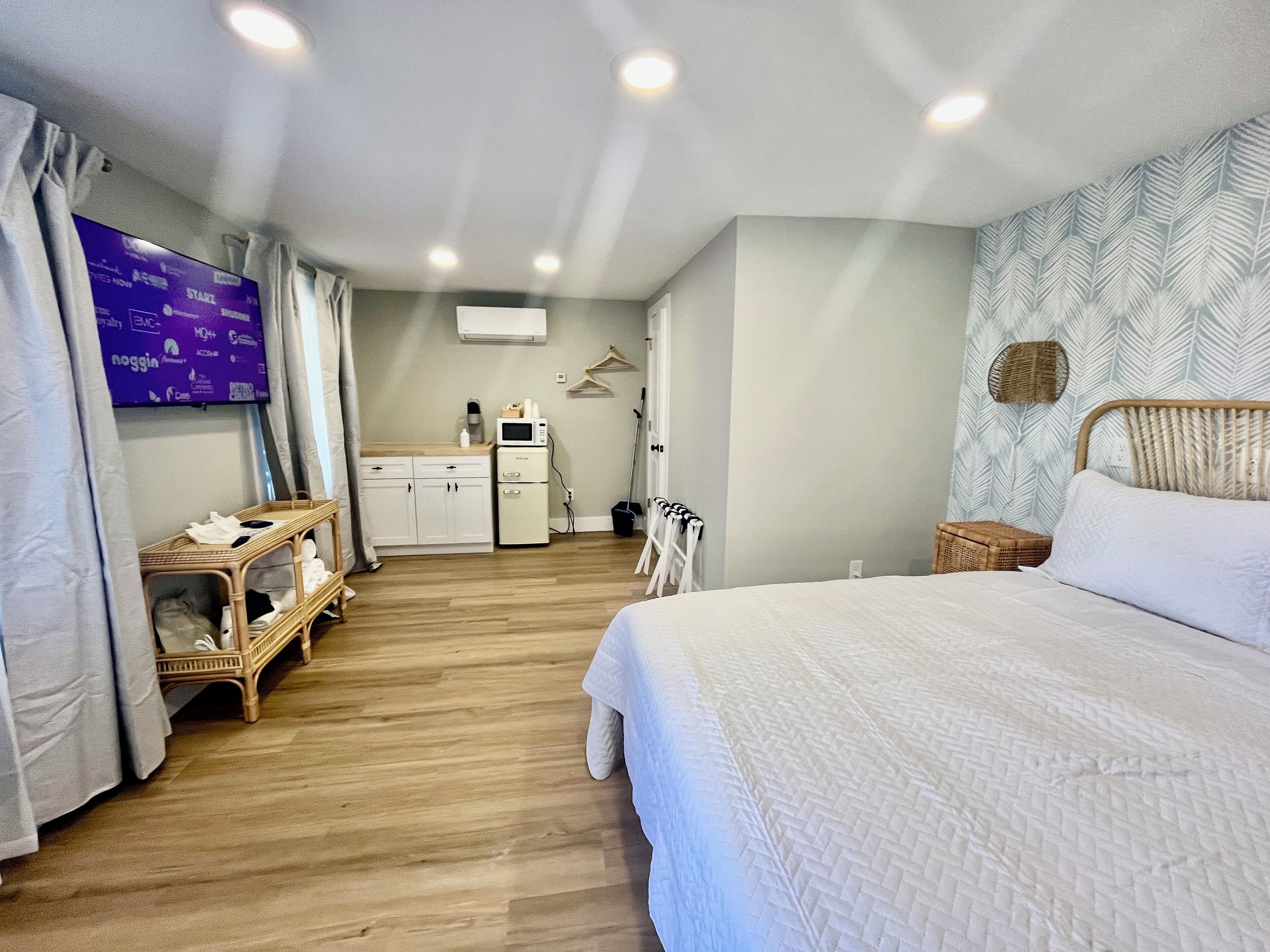 Ein Hotelzimmer mit Bett, einer kleinen Küchenzeile, einem Fernseher und einem Kleiderschrank.