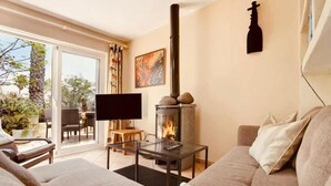 Ein Wohnzimmer mit Kamin, einer Couch, einem Fernseher und einem Glastisch.