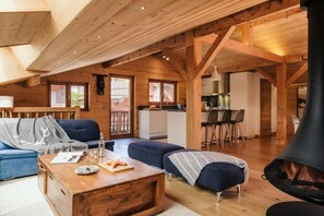 Un interior de cabaña acogedor con sala de estar, mesa de comedor, cocina y chimenea.