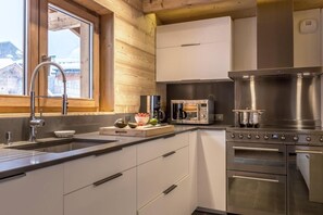 A modern kitchen with a stainless steel stove, a microwave, and a sink. - Chalet, 100m from ski slopes, balcony, fireplace or stove, tv, ski locker, 221m², La Clusaz (La Clusaz)