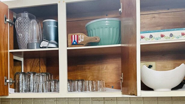 Eine Küchenschrank mit verschiedenen Gegenständen, darunter ein Mixer, ein Topf und Gläser.