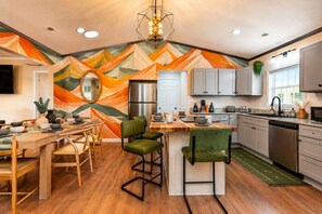 A modern kitchen with a central island, wooden dining table, and chairs.