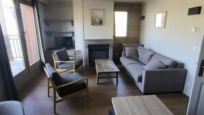A spacious living room with a sofa, chairs, a coffee table, and a fireplace. - 100m from ski slopes, 2nd floor, balcony, fireplace or stove, tv, ski locker, 64m², Val Thorens (Val Thorens)