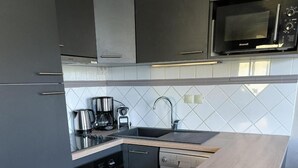 A modern kitchen with grey cabinetry, a wooden countertop island, a built-in oven, and a microwave above the sink. - 100m from ski slopes, 2nd floor, balcony, fireplace or stove, tv, ski locker, 64m², Val Thorens (Val Thorens)