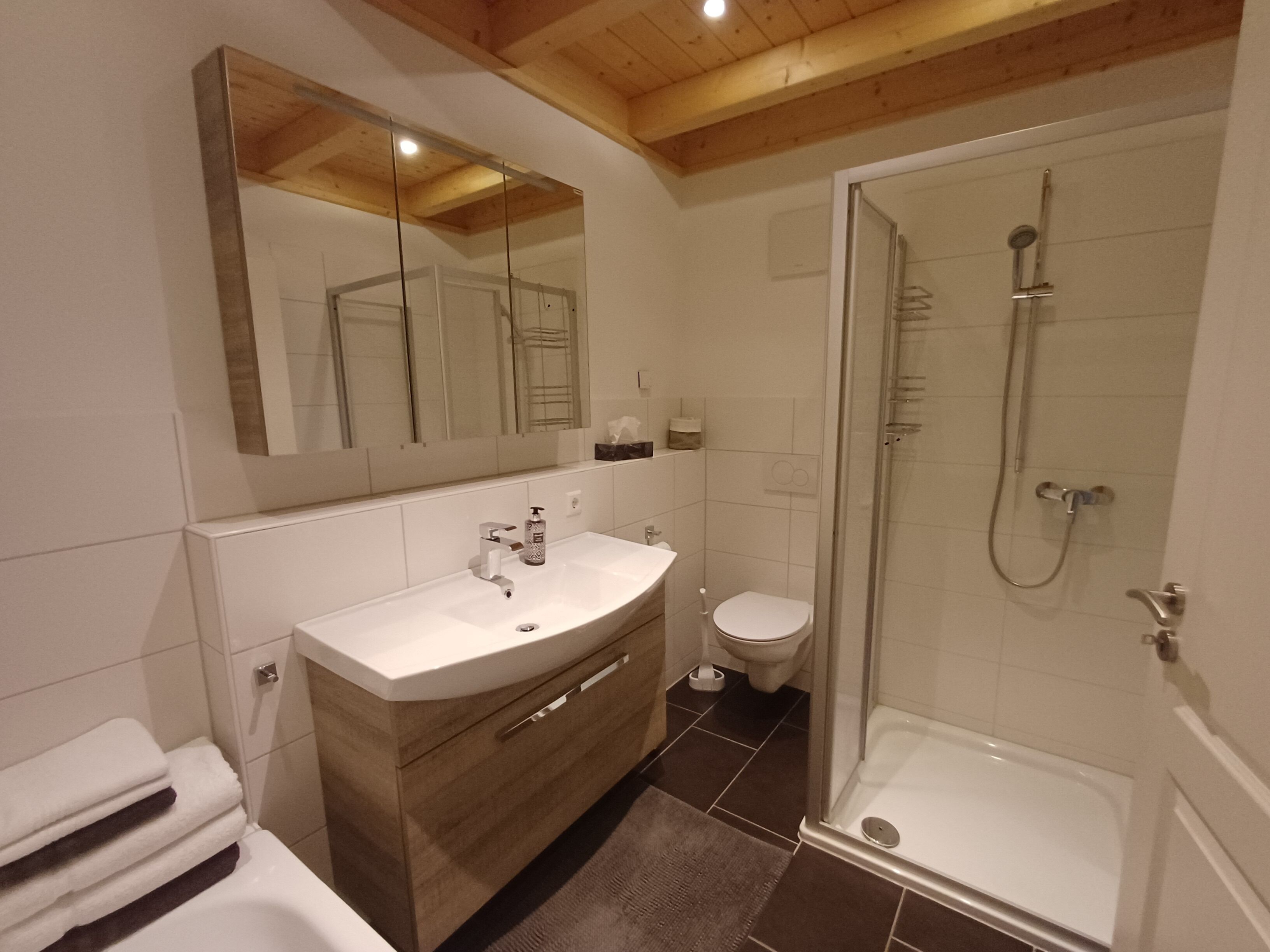 A modern bathroom with a vanity, toilet, and shower.