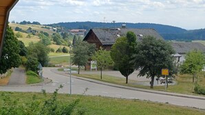 A rural road with a curve, surrounded by greenery and a distant mountain range.