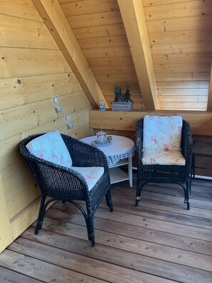A wooden deck with two wicker chairs and a small table, featuring a simple, rustic design. - Cozy and lovingly furnished vacation apartment in the Black Forest (Ibach)
